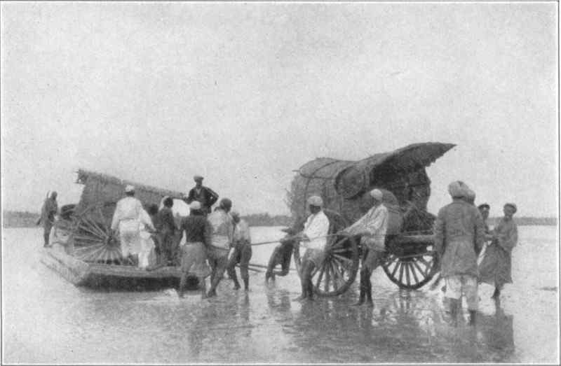 A cart being pulled through shallow water, with a second cart behind being unloaded from a wooden ferry.